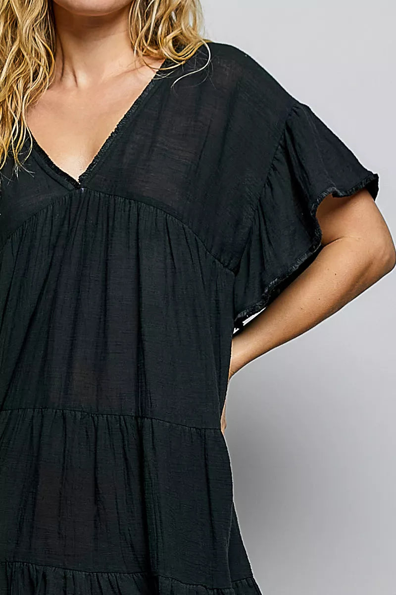 Woman wearing a black POL cotton dress featuring a V-neckline, tiered ruffle design, and relaxed flowy silhouette.
 Close View