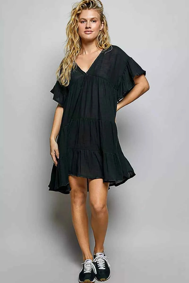 Woman wearing a black POL cotton dress featuring a V-neckline, tiered ruffle design, and relaxed flowy silhouette.
 Front full view