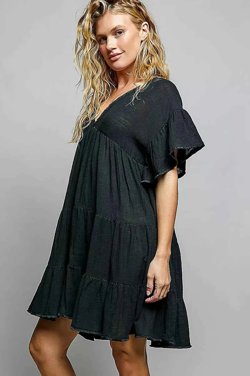 Woman wearing a black POL cotton dress featuring a V-neckline, tiered ruffle design, and relaxed flowy silhouette.
 Side View
