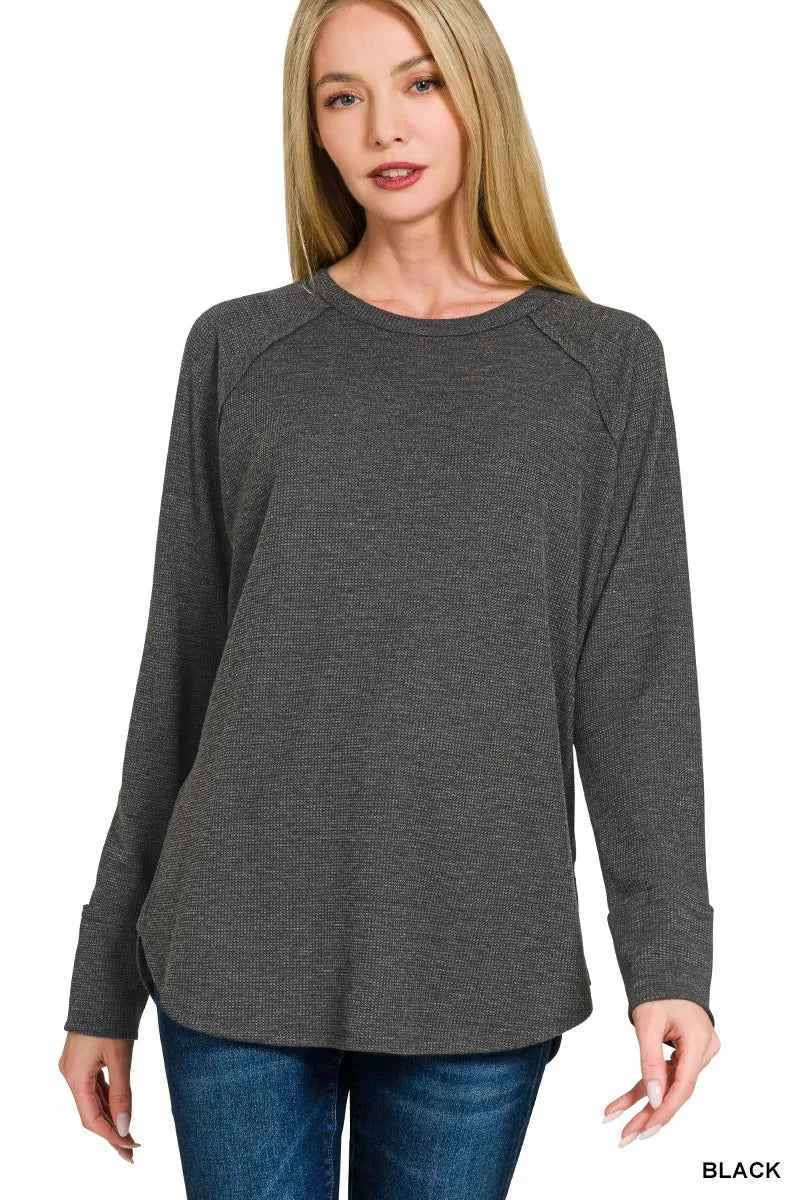 Woman wearing a black baby waffle knit long sleeve top by Zenana featuring raglan sleeves, a crew neckline, and a relaxed fit. Front View 2