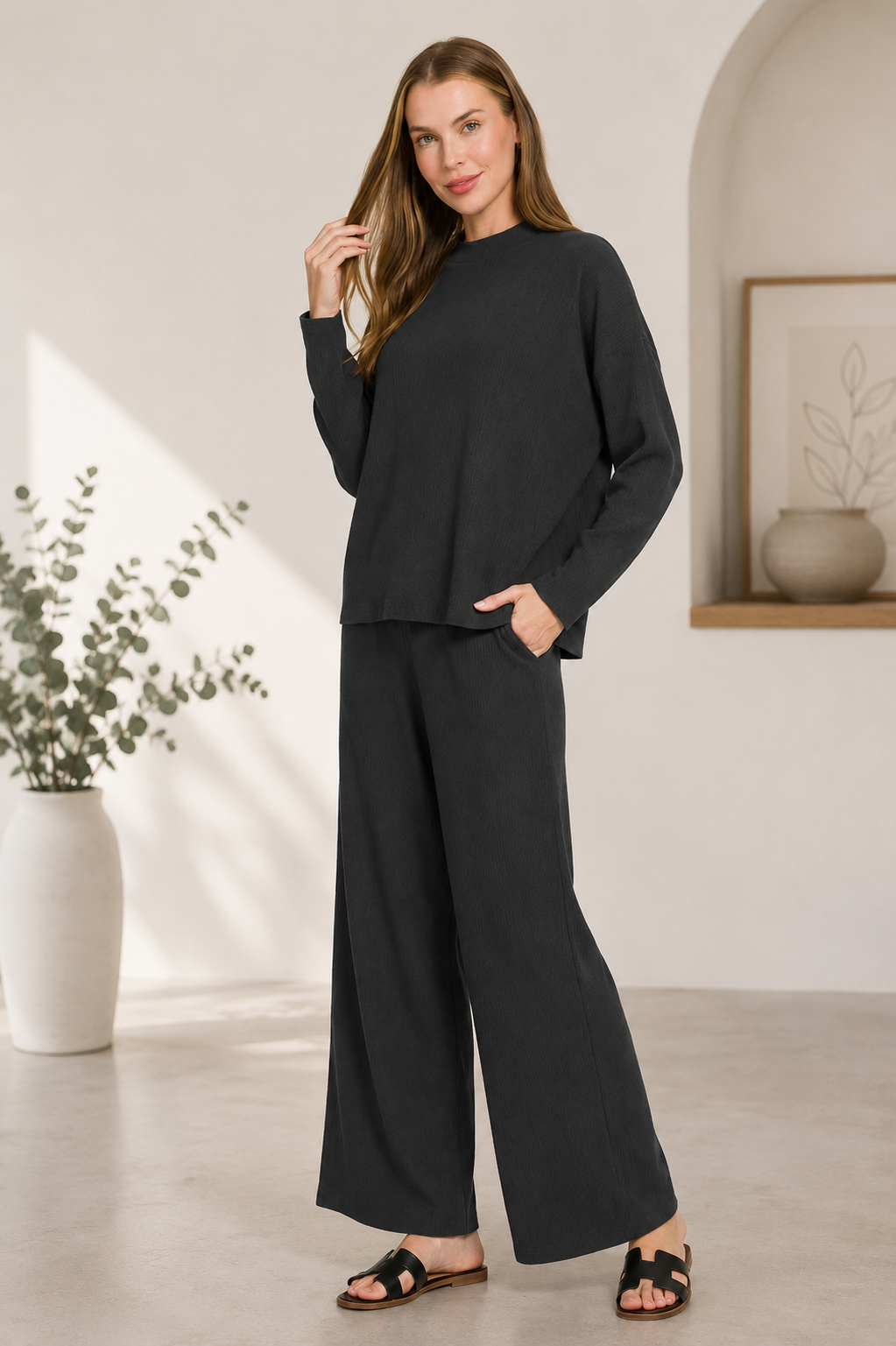 Woman wearing a black ribbed viscose long sleeve sweater with matching high-waisted wide leg pants by Zenana. front view