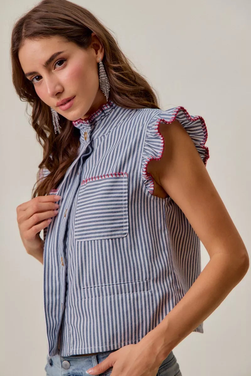 Woman wearing a blue and white striped sleeveless twill vest by SO ME featuring red whipstitch trim, ruffled collar, hidden button front and front pockets. Side View 2