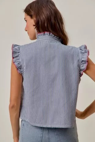 Woman wearing a blue and white striped sleeveless twill vest by SO ME featuring red whipstitch trim, ruffled collar, hidden button front and front pockets. Back View
