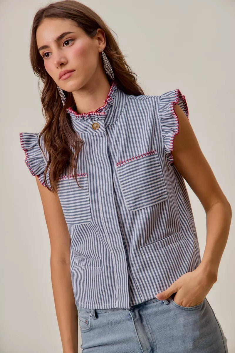 Woman wearing a blue and white striped sleeveless twill vest by SO ME featuring red whipstitch trim, ruffled collar, hidden button front and front pockets. Front View 2