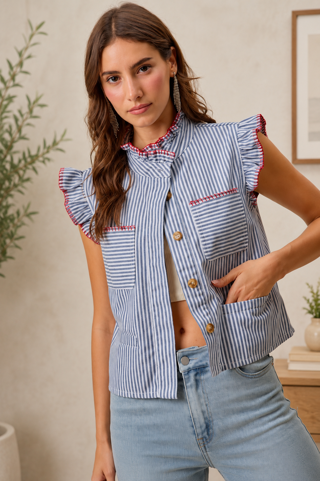 Woman wearing a blue and white striped sleeveless twill vest by SO ME featuring red whipstitch trim, ruffled collar, hidden button front and front pockets. Front view