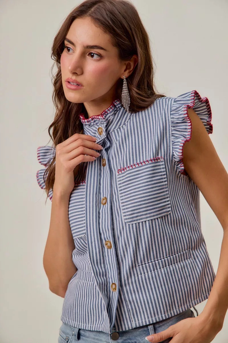 Woman wearing a blue and white striped sleeveless twill vest by SO ME featuring red whipstitch trim, ruffled collar, hidden button front and front pockets. Front view 3