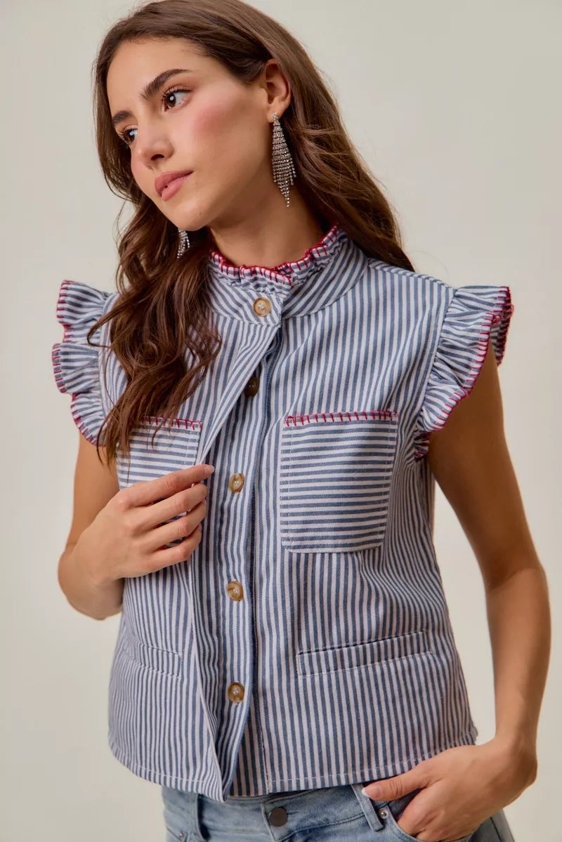 Woman wearing a blue and white striped sleeveless twill vest by SO ME featuring red whipstitch trim, ruffled collar, hidden button front and front pockets. Front view 6