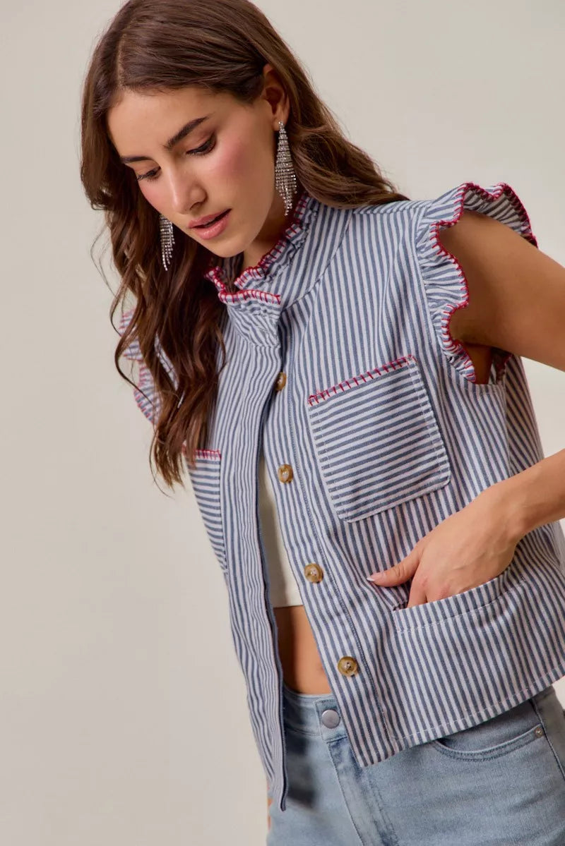 Woman wearing a blue and white striped sleeveless twill vest by SO ME featuring red whipstitch trim, ruffled collar, hidden button front and front pockets. Side View