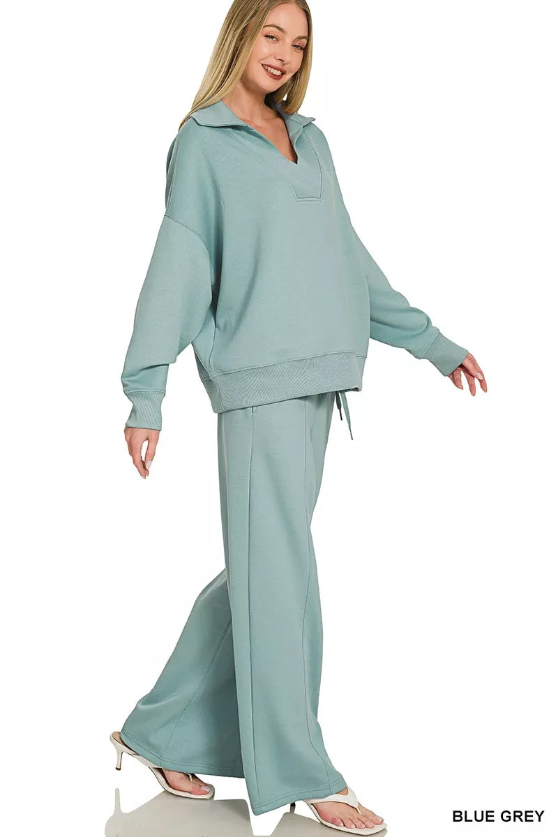 Woman wearing a blue grey Zenana scuba knit two-piece lounge set with a relaxed collared pullover and wide-leg center seam pants. Side View