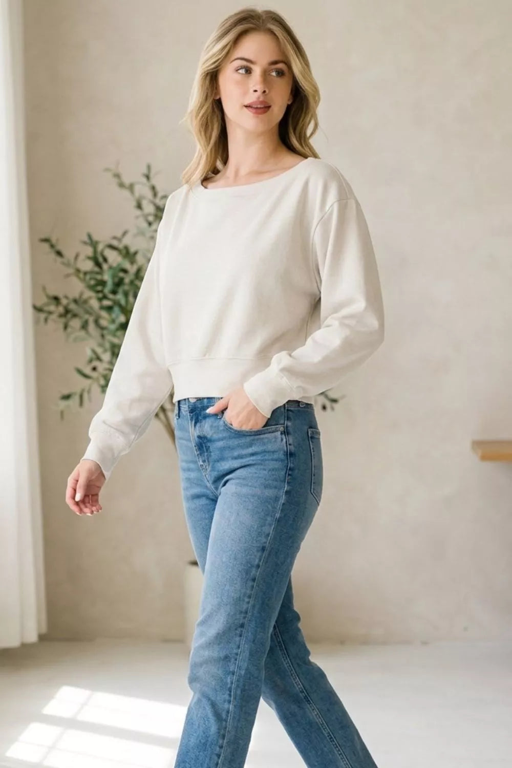 Woman wearing a bone scuba cropped boat neck pullover sweatshirt by Zenana. full View