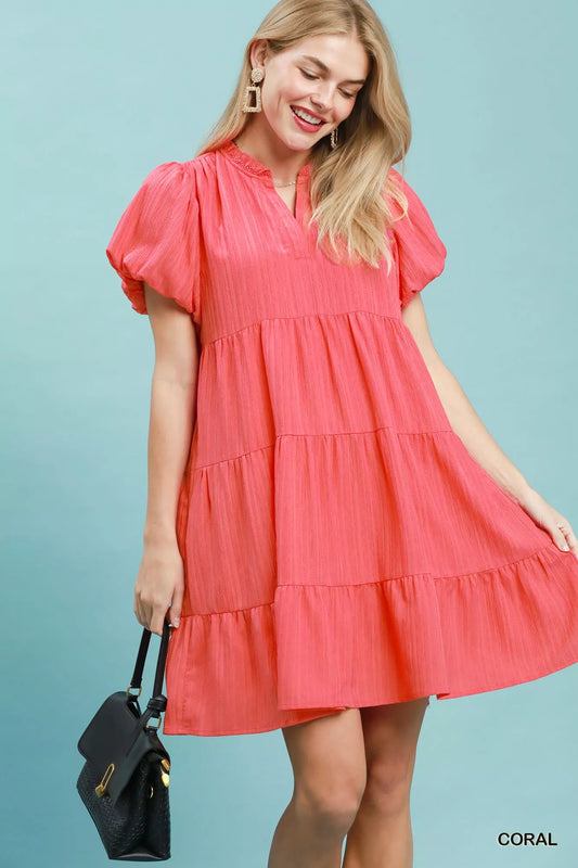 Woman wearing a coral tiered babydoll mini dress with puff sleeves and pockets by Umgee Front View