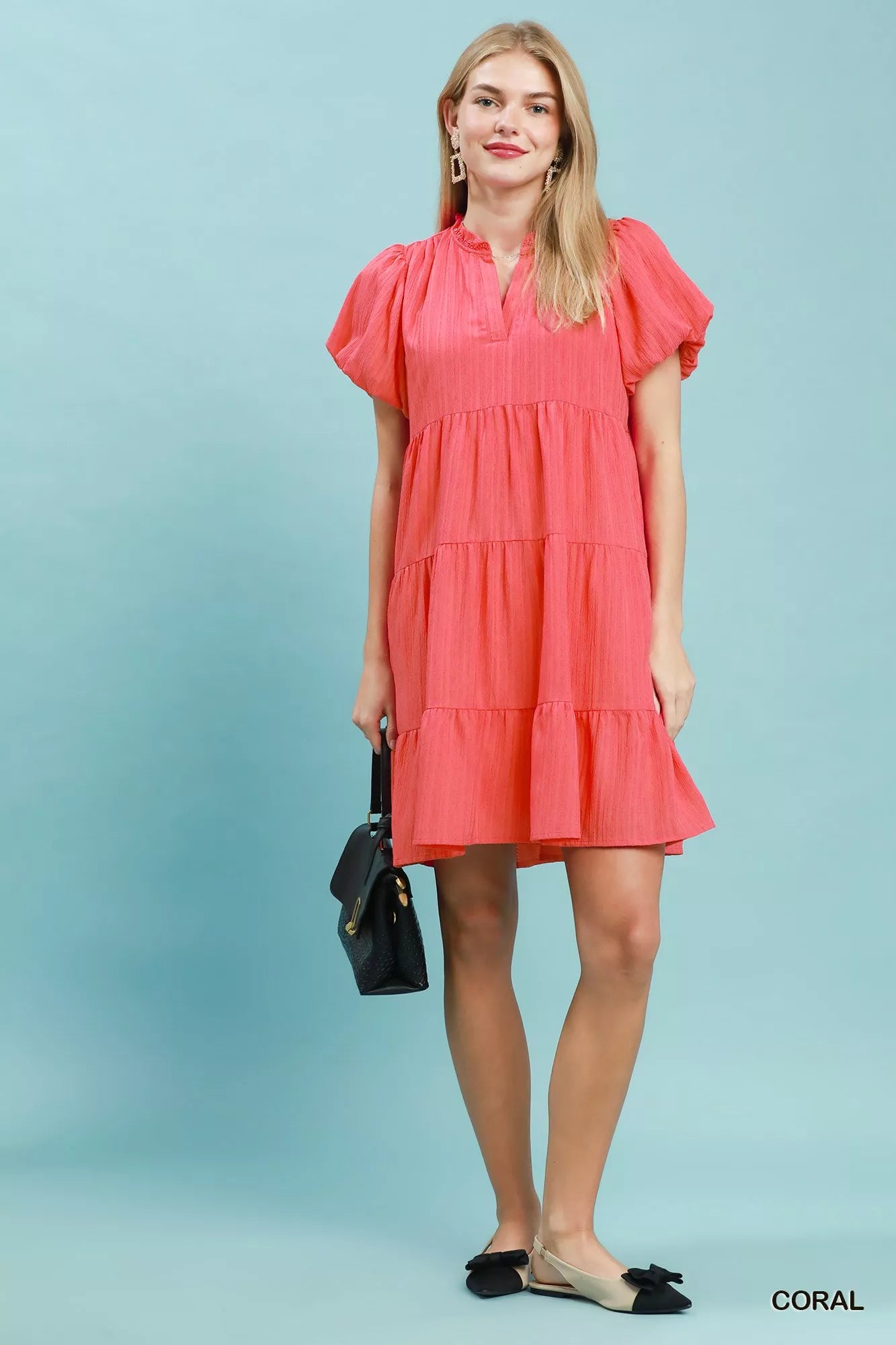 Woman wearing a coral tiered babydoll mini dress with puff sleeves and pockets by Umgee Full View