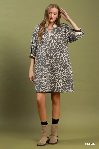Woman wearing a cream leopard print mini dress by Umgee featuring a quarter-zip neckline, puff sleeves, contrast trim, relaxed fit, and side pockets. full view