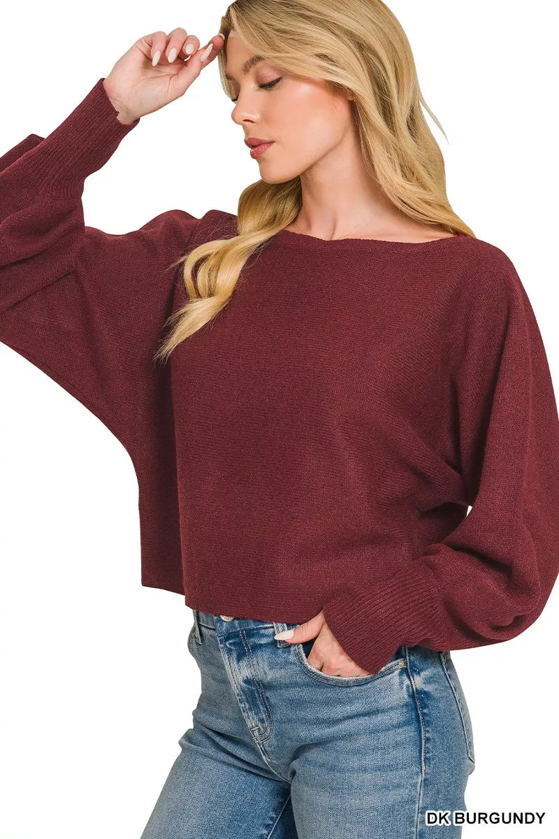 Woman wearing a dark burgundy boat neck sweater with oversized balloon sleeves, ribbed cuffs, and relaxed fit styled with blue denim jeans by Zenana. Side View