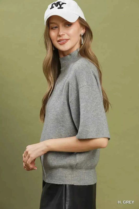 Woman wearing a heather grey mock neck short sleeve knit sweater top by Umgee. Side View