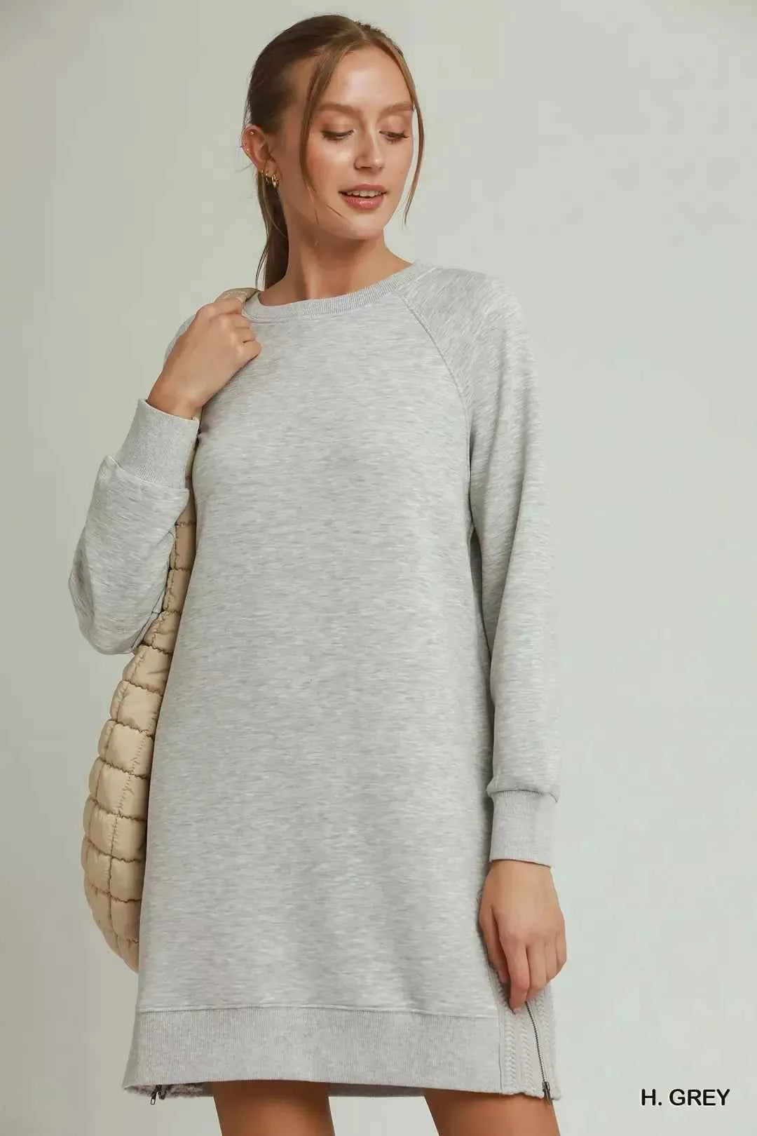 Woman wearing a heather grey sweatshirt dress with side crochet trim, zipper details, pockets, and long sleeves by Umgee. Front View