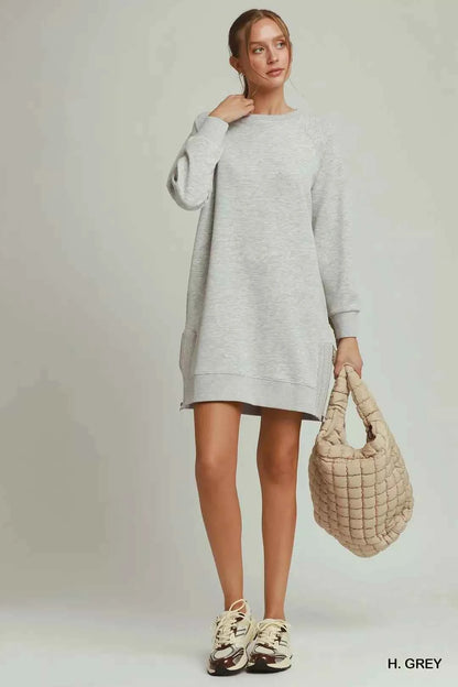 Woman wearing a heather grey sweatshirt dress with side crochet trim, zipper details, pockets, and long sleeves by Umgee. Full View