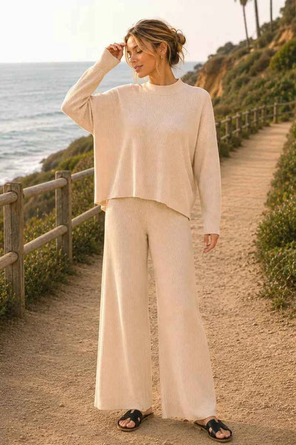 Woman wearing a light beige ribbed sweater and matching wide-leg pants set by Zenana featuring a relaxed fit and soft knit fabric. Front view