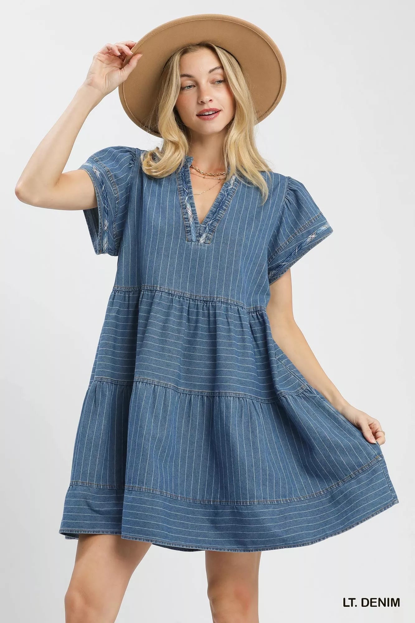 Woman wearing a light denim pinstripe chambray tiered babydoll dress with flutter sleeves and pockets by Umgee Front View