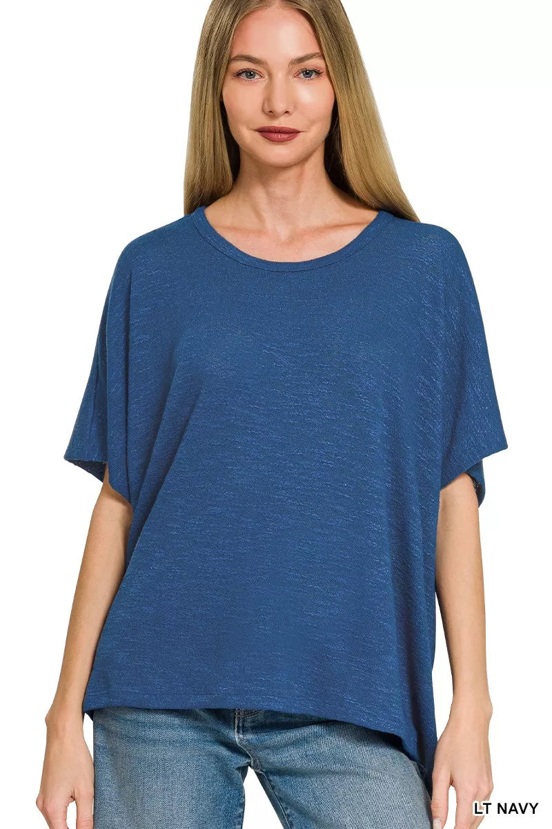 Woman wearing a light navy oversized slub hacci knit top by Zenana featuring a relaxed fit, short sleeves, crew neckline, and draped hem. Front view 2