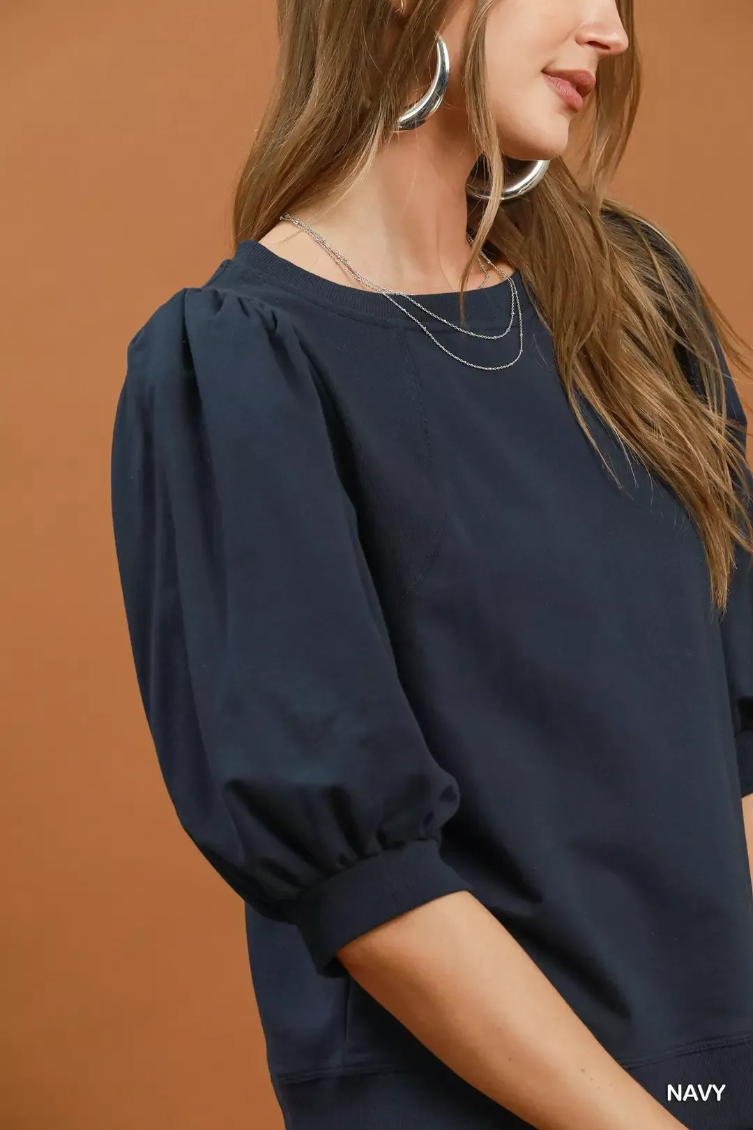 Woman wearing a navy puff sleeve cotton sweatshirt by Umgee paired with leopard print pants for an elevated casual outfit. Close View
