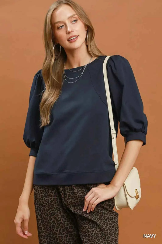 Woman wearing a navy puff sleeve cotton sweatshirt by Umgee paired with leopard print pants for an elevated casual outfit. Front View
