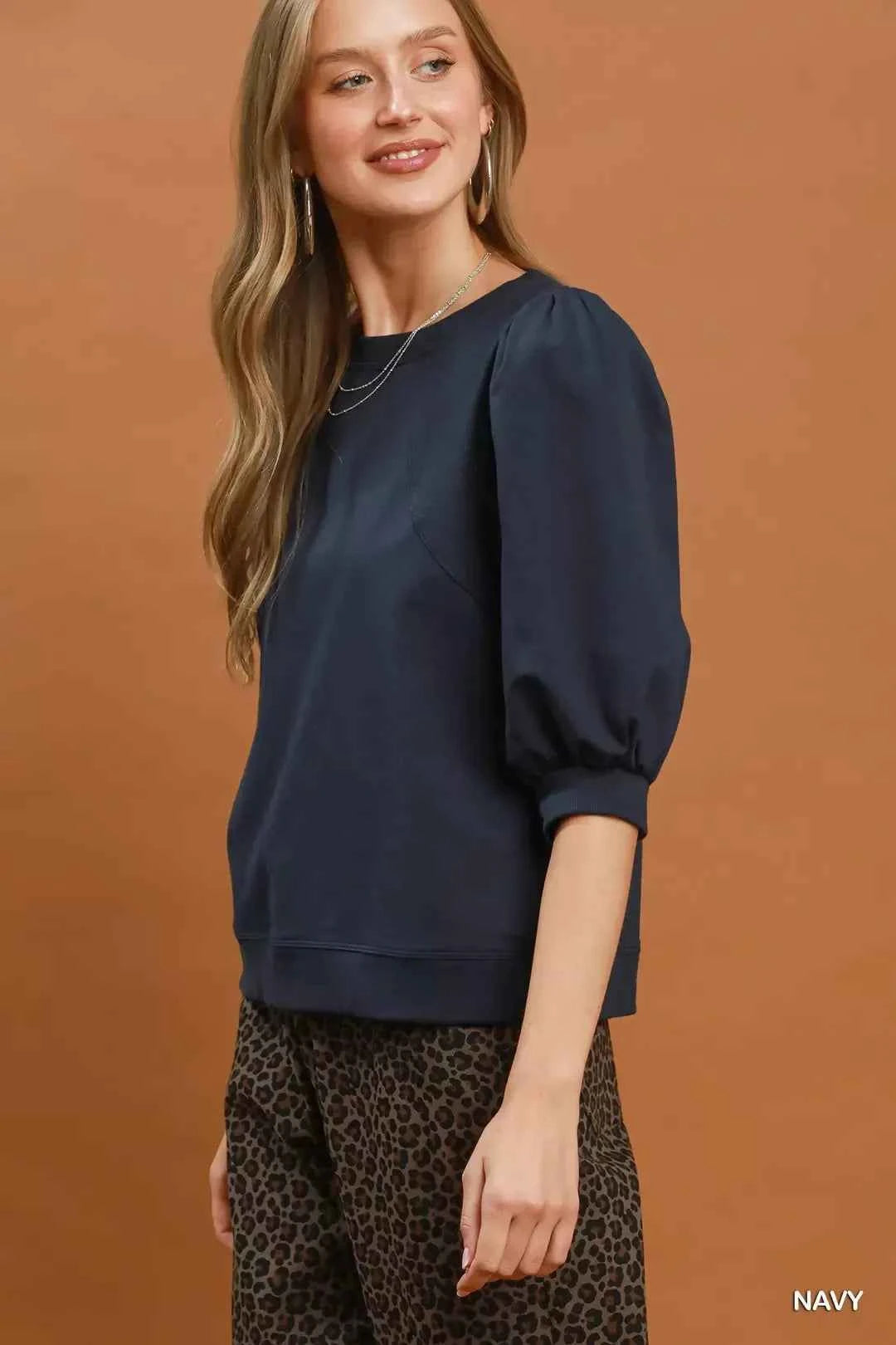 Woman wearing a navy puff sleeve cotton sweatshirt by Umgee paired with leopard print pants for an elevated casual outfit. Side View