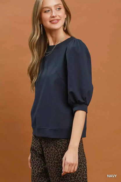 Woman wearing a navy puff sleeve cotton sweatshirt by Umgee paired with leopard print pants for an elevated casual outfit. Side View