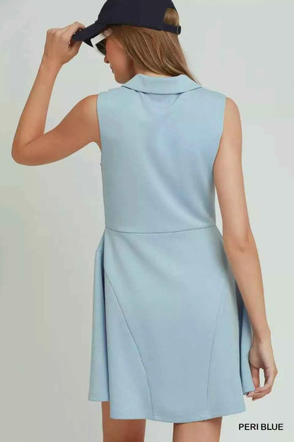 Woman wearing a peri blue sleeveless quarter zip collared athleisure dress by Umgee with a flared skirt and sporty summer styling. Back View