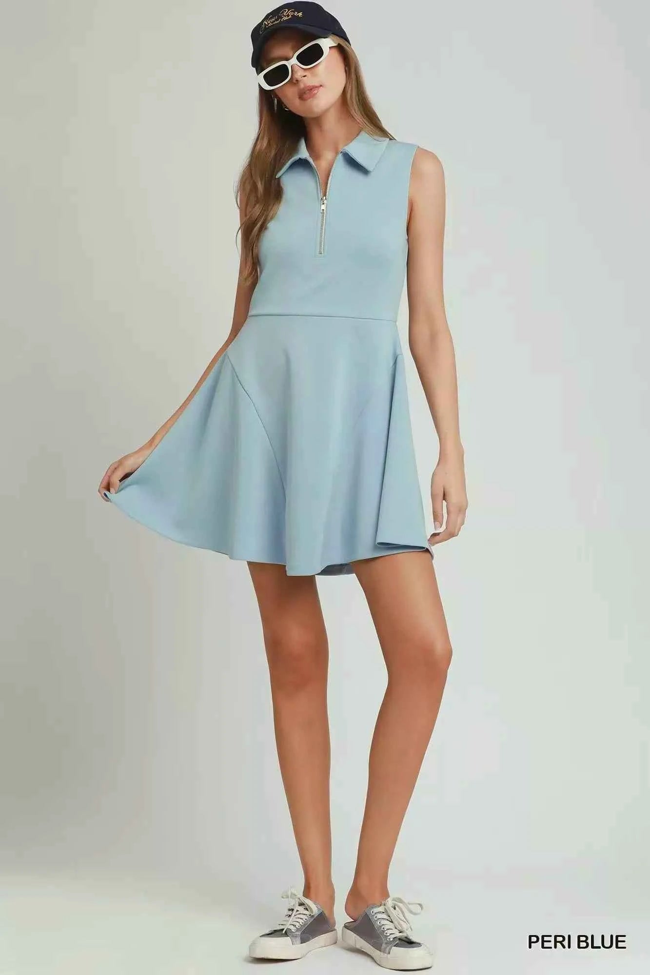 Woman wearing a peri blue sleeveless quarter zip collared athleisure dress by Umgee with a flared skirt and sporty summer styling. Front View