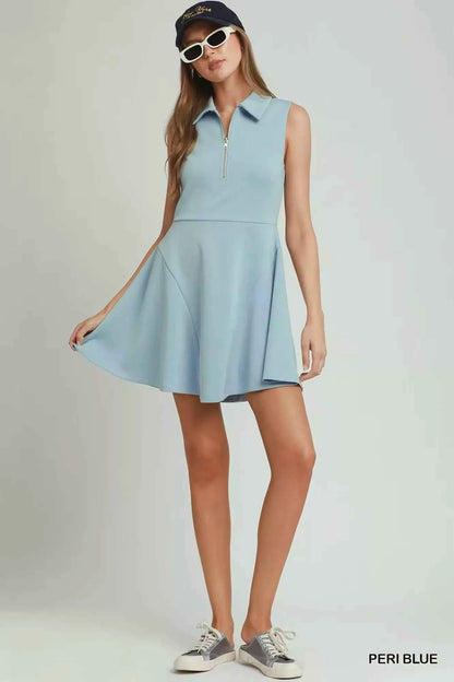 Woman wearing a peri blue sleeveless quarter zip collared athleisure dress by Umgee with a flared skirt and sporty summer styling. Front View
