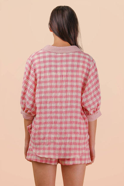 Woman wearing a pink and white gingham button-down shirt and matching drawstring shorts set back view