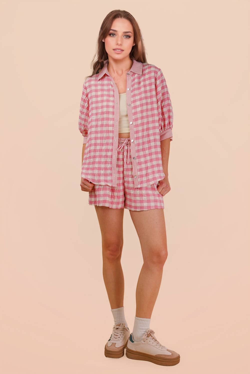 Woman wearing a pink and white gingham button-down shirt and matching drawstring shorts set full view