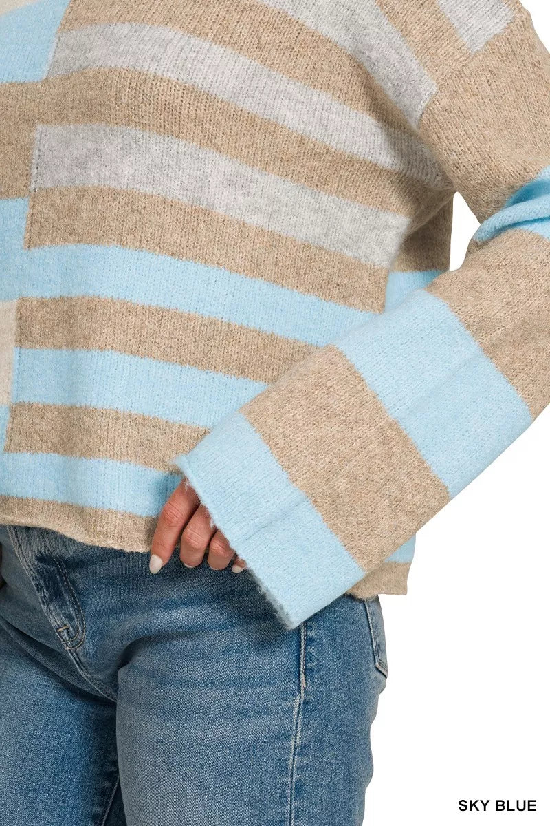 Woman wearing a sky blue, ivory, and oatmeal color block lightweight wool blend sweater by Zenana paired with blue jeans. Close View