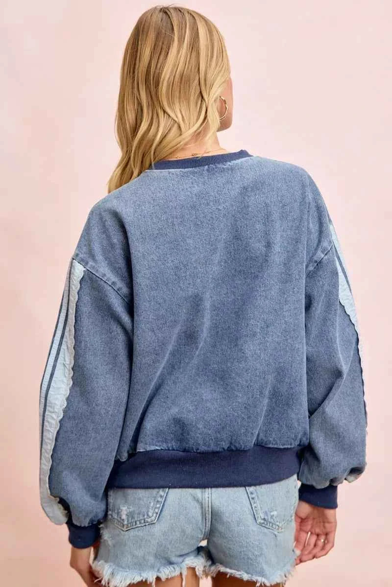Woman wearing a washed denim lace contrast sweatshirt with long sleeves and relaxed fit by BiBi. Back View