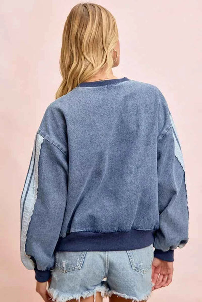 Woman wearing a washed denim lace contrast sweatshirt with long sleeves and relaxed fit by BiBi. Back View