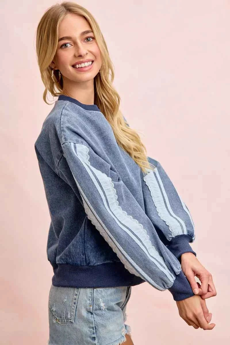Woman wearing a washed denim lace contrast sweatshirt with long sleeves and relaxed fit by BiBi. Side View