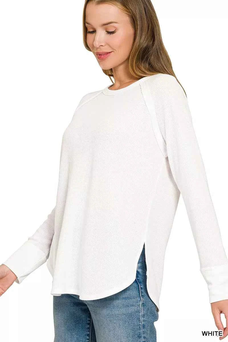 Woman wearing a white baby waffle knit long sleeve top by Zenana featuring raglan sleeves, a curved hem, and a relaxed everyday fit. Side View