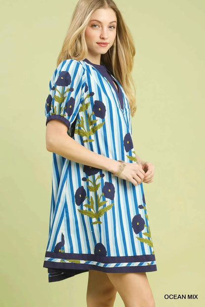 Woman wearing an Ocean Blue mixed floral and stripe print cotton dress with a split V-neckline and contrast trim by Umgee. side view