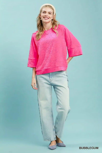 Woman wearing an Umgee bubblegum pink floral textured terry top featuring embossed floral patterns, a relaxed fit, round neckline, and three-quarter sleeves. Full View