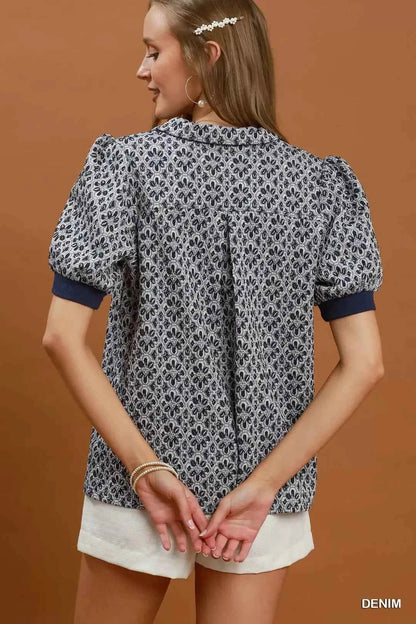 Woman wearing an Umgee denim blue printed puff sleeve collared blouse with a floral-inspired print and V-neck collar. Back View