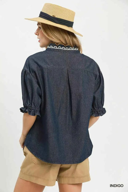 Woman wearing an Umgee indigo chambray button front blouse with lace trim neckline and puff sleeves styled with casual shorts. Back View