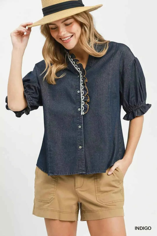 Woman wearing an Umgee indigo chambray button front blouse with lace trim neckline and puff sleeves styled with casual shorts. Front View