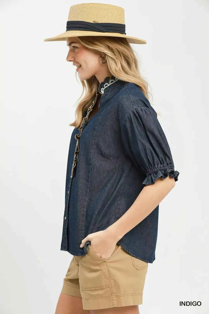 Woman wearing an Umgee indigo chambray button front blouse with lace trim neckline and puff sleeves styled with casual shorts. Side View