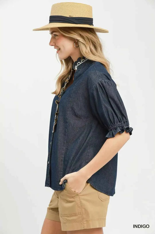 Woman wearing an Umgee indigo chambray button front blouse with lace trim neckline and puff sleeves styled with casual shorts. Side View