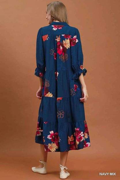 Woman wearing an Umgee navy floral tiered midi dress with puff sleeves, pockets, and a flowy feminine silhouette. Back View