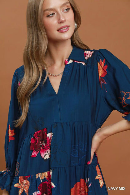 Woman wearing an Umgee navy floral tiered midi dress with puff sleeves, pockets, and a flowy feminine silhouette. Close View