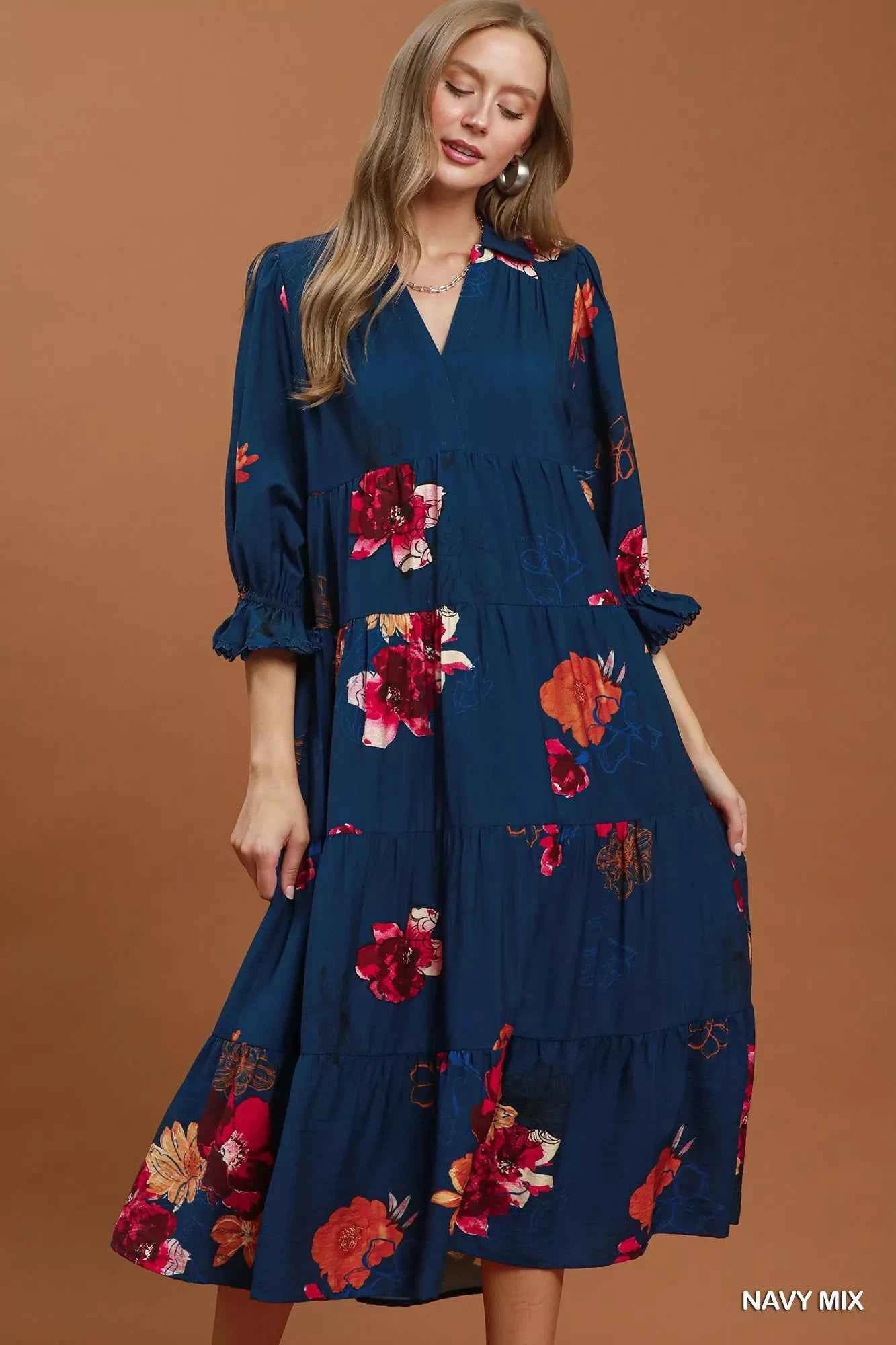 Woman wearing an Umgee navy floral tiered midi dress with puff sleeves, pockets, and a flowy feminine silhouette. Front view