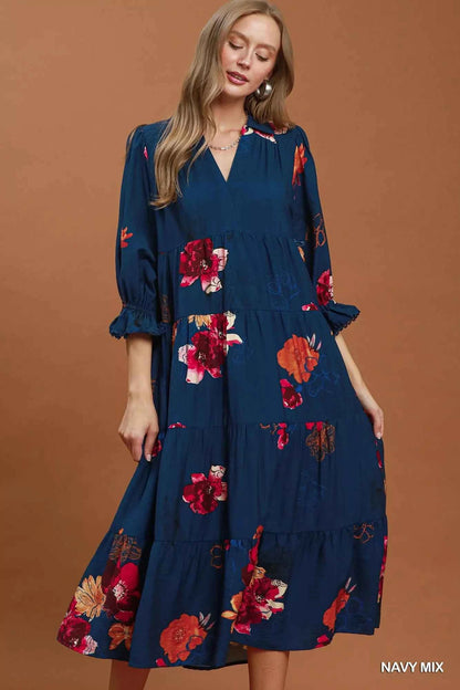 Woman wearing an Umgee navy floral tiered midi dress with puff sleeves, pockets, and a flowy feminine silhouette. Front view