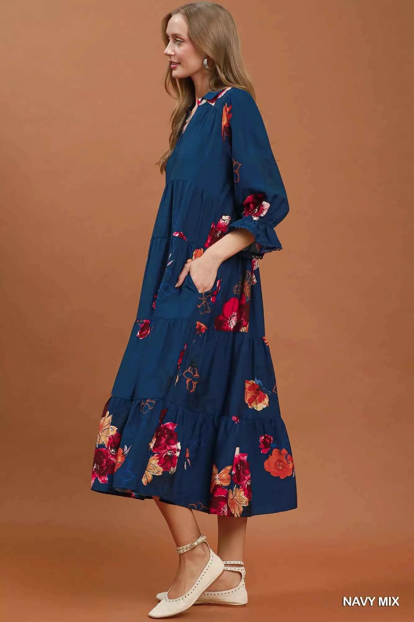Woman wearing an Umgee navy floral tiered midi dress with puff sleeves, pockets, and a flowy feminine silhouette. Side View
